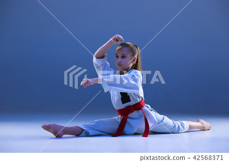 Young girl training karate on blue background Young girl training karate on blue background 42568371