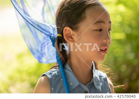 A happy girl trying to catch a dragonfly A happy girl trying to catch a dragonfly 42570040