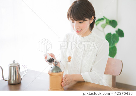 把咖啡豆放的婦女在咖啡碾裡 42570453