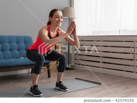 Happy fitness woman doing squat exercise at home 42574159