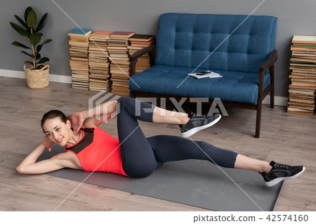 Fitness woman doing bicycle crunch workout on mat at home 42574160