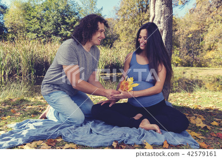 Man giving autumn leaves to his pregnant wife  42579161