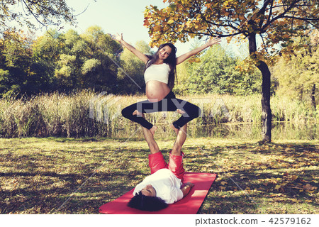 Young couple doing acro yoga. Pregnant woman  42579162