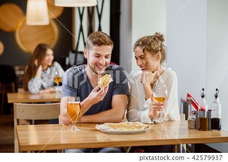 Sweet couple eating pizza and drinking beer and wine in pizzeria. Sweet couple eating pizza and drinking beer and wine in pizzeria. 42579937