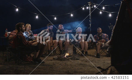 Young people watching movies near campfire 42583151