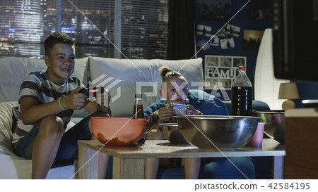 Teen boys playing videogame together on sofa Teen boys playing videogame together on sofa 42584195