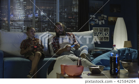 Playful father and son having fun and playing videogame Playful father and son having fun and playing videogame 42584204