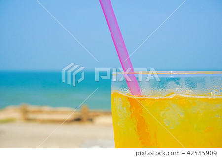 Orange juice drinking on the beach Orange juice drinking on the beach 42585909