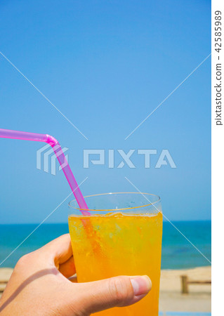 Orange juice drinking on the beach 42585989