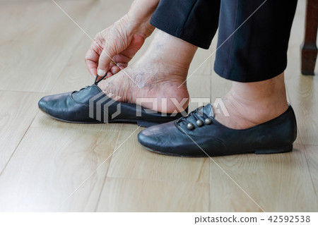 Elderly woman putting on shoes. 42592538
