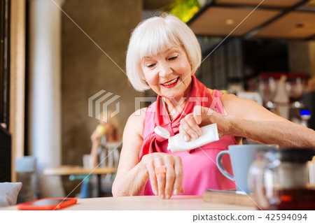 Cheerful aged woman holding a bottle of cream 42594094