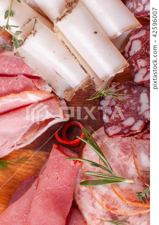 Cold smoked meat plate with pork, prosciutto, salami on wooden background. Mustard sauce and garlic Cold smoked meat plate with pork, prosciutto, salami on wooden background. Mustard sauce and garlic 42596007