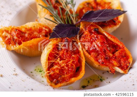 Italian pasta Conchiglioni Rigati. Delicious dish stuffed with ground meat with dry tomatoes in Italian pasta Conchiglioni Rigati. Delicious dish stuffed with ground meat with dry tomatoes in 42596115