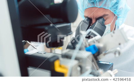 Doctor or scientist looking through microscope in lab 42596458
