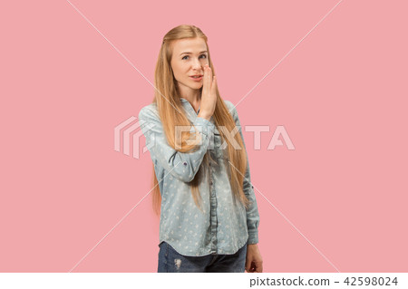 The young woman whispering a secret behind her hand over pink background The young woman whispering a secret behind her hand over pink background 42598024