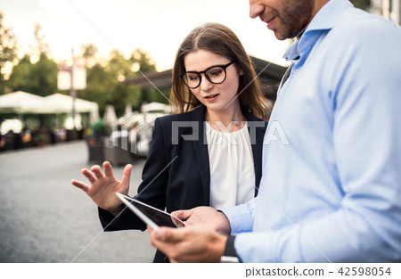 A young businessman and businesswoman using tablet outdoors. A young businessman and businesswoman using tablet outdoors. 42598054