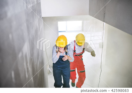 Woman and man workers running up the stairs at the construction site. 42598083