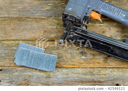 Nail gun and nails on pine wood table Nail gun and nails on pine wood table 42599121