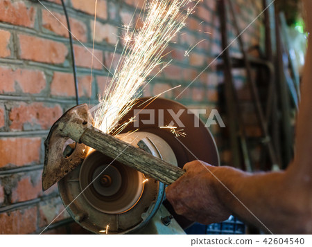farmer sharpens garden tool on electric grindstone 42604540