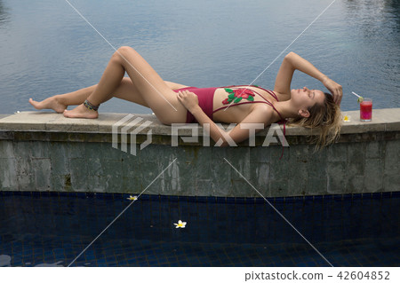 Beautiful young woman laying and relaxing in pool Beautiful young woman laying and relaxing in pool 42604852