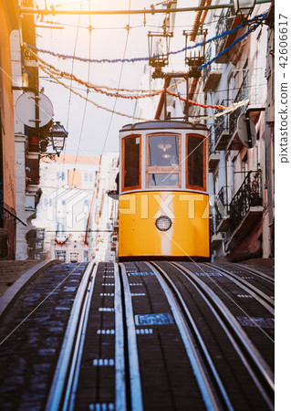 Lisbon's Gloria yellow funicular drives down the street. Lisbon, Portugal. West side of the Avenida Lisbon's Gloria yellow funicular drives down the street. Lisbon, Portugal. West side of the Avenida 42606617