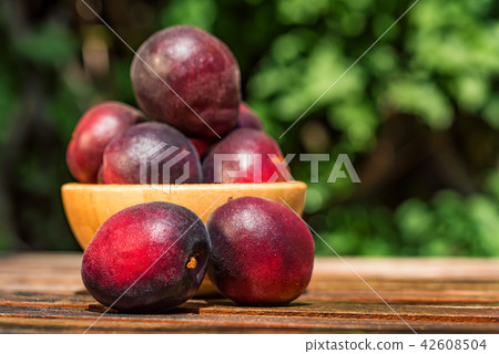Pluot, mix of plum and apricot in wooden bowl Pluot, mix of plum and apricot in wooden bowl 42608504