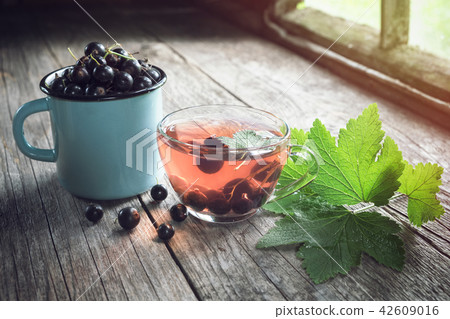 Black currants, glass cup of fruit tea. 42609016