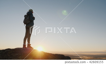 Crane shot: A woman traveler stands on top of a mountain, looks at the beautiful landscape ahead 42609155