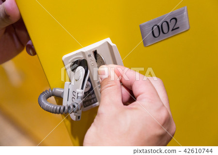 A man who puts money into a coin locker 42610744