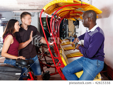 Dissatisfied African-American man driver of rickshaw talking with couple Dissatisfied African-American man driver of rickshaw talking with couple 42615338