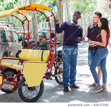 Smiling African-American bikecab driver talking to young couple Smiling African-American bikecab driver talking to young couple 42615340