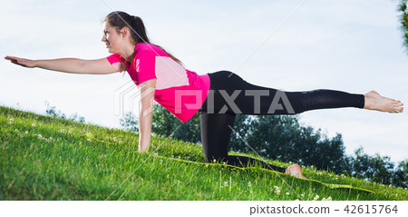 Female in pink T-shirt is practising asanas Female in pink T-shirt is practising asanas 42615764