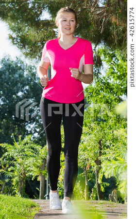 Sporty girl in pink T-shirt is running around Sporty girl in pink T-shirt is running around 42615774