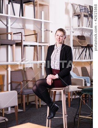 Salesgirl sitting on chair in furniture shop 42615868