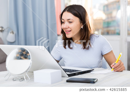 Young woman student working with laptop and pen at table Young woman student working with laptop and pen at table 42615885