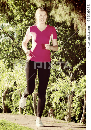 Young girl in pink T-shirt is jogging 42616088