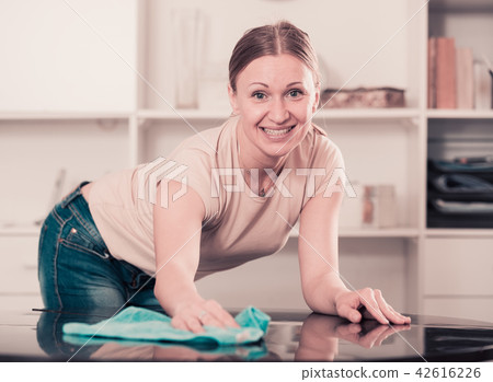 Smiling woman wiping table Smiling woman wiping table 42616226