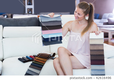 Glad woman touching color textile for sofa 42616496