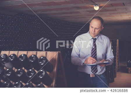 Winemaker with clipboard in winery vault 42616886