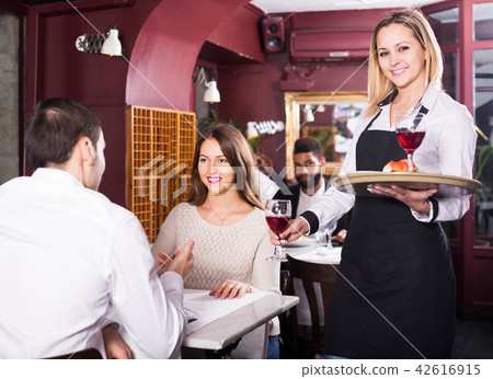 waitress serving meal for young couple at table 42616915