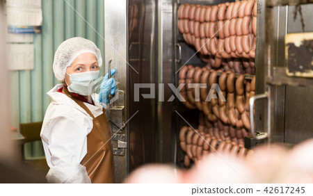 Woman checking sausages in baking machine 42617245