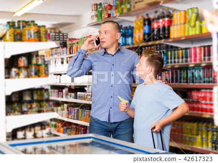 Man talking on phone while visiting supermarket Man talking on phone while visiting supermarket 42617323
