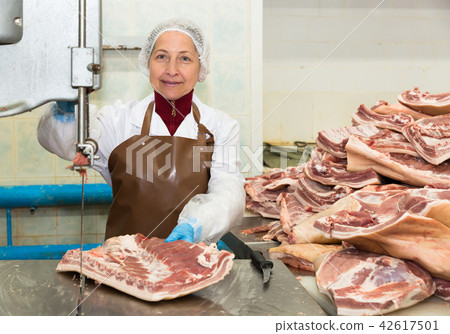 Smiling woman working on meat cutting band saw Smiling woman working on meat cutting band saw 42617501