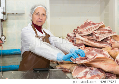 Workwoman cutting meat on band cutting saw 42617521