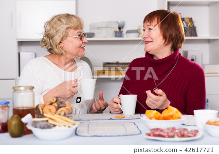 Positive old women drinking tea at the table Positive old women drinking tea at the table 42617721