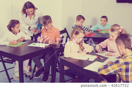 Children in elementary age drawing together at classroom 42617722