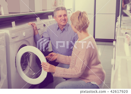 friendly mature couple chooses washing machine for their house in shop of household appliances 42617920