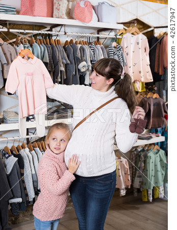 Mother and small daughter choosing clothes for baby Mother and small daughter choosing clothes for baby 42617947