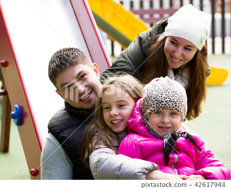 Happy family of four at children's playground Happy family of four at children's playground 42617948