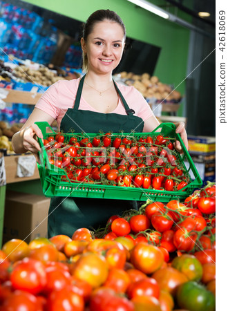 Salesgirl in store with crate of tomatoes 42618069